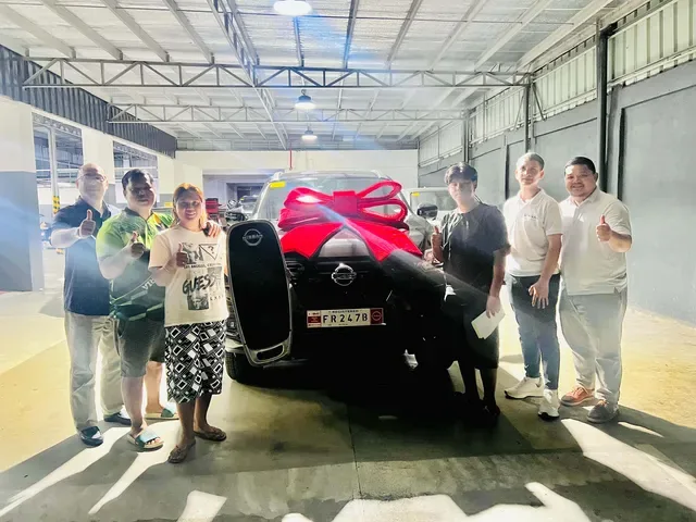 A family and staff celebrating a Nissan delivery at the dealership
